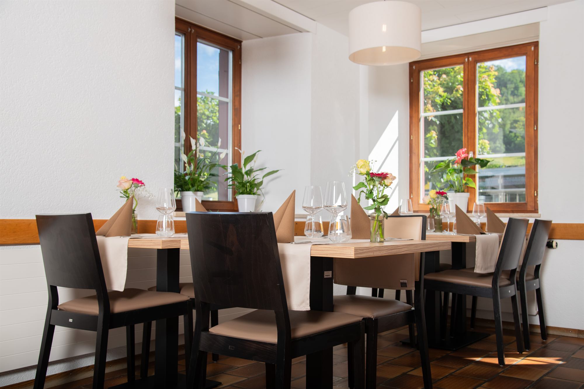 Heller Restaurantsaal bei Tageslicht mit gedeckten Tischen.