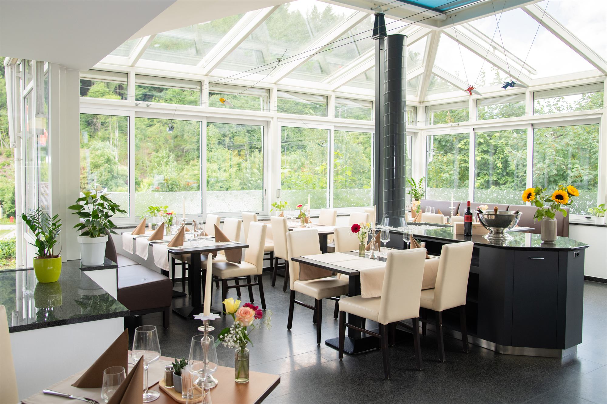Der lichtdurchflutete Wintergarten des Talhaus mit Blick ins Grüne.